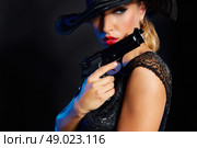 Fashion woman gangster style with handgun pistol on black background. Стоковое фото, агентство Ingram Publishing / Фотобанк Лори