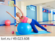 Pilates woman side bend fitball exercise workout at gym indoor swiss ball. Стоковое фото, агентство Ingram Publishing / Фотобанк Лори