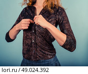 A young woman is buttoning her faux leather shirt. Стоковое фото, агентство Ingram Publishing / Фотобанк Лори