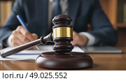Male lawyer working. Judge or solicitor writes notes in notebook. Judge's wooden hammer on wooden table in lawyer office or courtroom against background of man signing documents. Стоковое AI-видео, аниматор Ирина / Фотобанк Лори