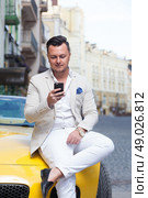 Stylish man using smartphone near sport car. Стоковое фото, агентство Ingram Publishing / Фотобанк Лори