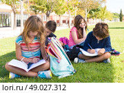 Group of little students sitting on the grass at school. Стоковое фото, агентство Ingram Publishing / Фотобанк Лори