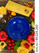 Raw pasta with ingridients and blue plate. Pasta with ingridients and empty blue plate. Стоковое фото, агентство Ingram Publishing / Фотобанк Лори