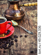 Coffee and cezve. Red coffee Cup and saucer on the background of spilling the beans and cezve. Стоковое фото, агентство Ingram Publishing / Фотобанк Лори