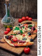 flavorful homemade pizza with bacon. hunk of delicious meat pizza with bacon and olives on the background of the vegetables.The image is tinted. Стоковое фото, агентство Ingram Publishing / Фотобанк Лори