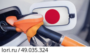 The Japanese flag on the lid of the gas tank of a car at a gas station in close-up. High or low gasoline prices at Japan gas stations. Gasoline prices are rising due to a shortage of diesel fuel. Стоковое фото, фотограф Владимир Разгуляев / Фотобанк Лори
