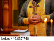 The priest's hands hold a cross against a background of flickering candles. Religion and faith. Стоковое фото, фотограф Лазаренко Светлана / Фотобанк Лори
