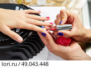 Nails painting with UV dry lamp in blue light woman hands at nail salon. Стоковое фото, агентство Ingram Publishing / Фотобанк Лори