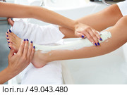 Pedicure aplying nourishing moisturizer mask in legs of woman in nails salon. Стоковое фото, агентство Ingram Publishing / Фотобанк Лори