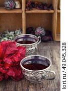 Tea from Sudanese rose. Medicinal tea a decoction of hibiscus tea in stylish cups. Стоковое фото, агентство Ingram Publishing / Фотобанк Лори