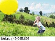 Joyful boy bouncing a yellow balloon. Стоковое фото, агентство Ingram Publishing / Фотобанк Лори