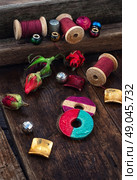 Beads,spools of thread on vintage wooden background decorated with rosebuds. Стоковое фото, агентство Ingram Publishing / Фотобанк Лори