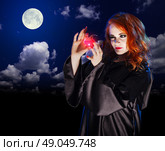 Young witch with potion on night sky background. Стоковое фото, агентство Ingram Publishing / Фотобанк Лори