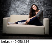 Young girl sit on sofa at dark room. Стоковое фото, агентство Ingram Publishing / Фотобанк Лори