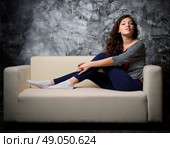 Young girl on sofa at dark room. Стоковое фото, агентство Ingram Publishing / Фотобанк Лори