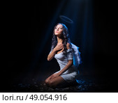 Young woman in an image of angel at dark room. Стоковое фото, агентство Ingram Publishing / Фотобанк Лори