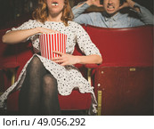 A young woman is eating popcorn loudly in a movie theater and is annoying the man sitting behind her. Стоковое фото, агентство Ingram Publishing / Фотобанк Лори
