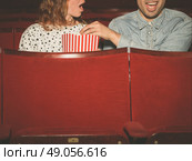 A young couple is watching a film in a movie theater and the man is stealing the woman’s popcorn to her dismay. Стоковое фото, агентство Ingram Publishing / Фотобанк Лори