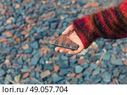 A womans hand is holding a piece of slate outside with gravel and rubble on the ground. Стоковое фото, агентство Ingram Publishing / Фотобанк Лори