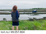 A young woman is walking in the marshes and is looking at a boat. Стоковое фото, агентство Ingram Publishing / Фотобанк Лори