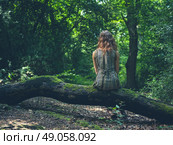 A young woman is sitting on a log in a clearing in the forest. Стоковое фото, агентство Ingram Publishing / Фотобанк Лори