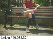 A young woman wearing knee high socks is sitting on a park bench. Стоковое фото, агентство Ingram Publishing / Фотобанк Лори