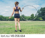 A fit and athletic young woman is twirling a hula hoop in the park on a sunny summer day. Стоковое фото, агентство Ingram Publishing / Фотобанк Лори