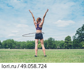 A fit and athletic young woman is working out with a hula hoop in the park on a sunny summer day. Стоковое фото, агентство Ingram Publishing / Фотобанк Лори