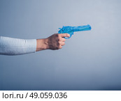 A male hand is holding a blue water pistol and is aiming it. Стоковое фото, агентство Ingram Publishing / Фотобанк Лори