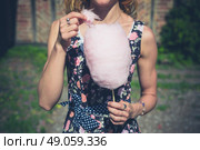 A young woman wearing a dress is standing outside an old farmhouse with a candyfloss on a sunny summer day. Стоковое фото, агентство Ingram Publishing / Фотобанк Лори
