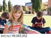Group of little students sitting on the grass at school. Стоковое фото, агентство Ingram Publishing / Фотобанк Лори