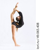 Young girl engaged art gymnastic on grey. Стоковое фото, агентство Ingram Publishing / Фотобанк Лори