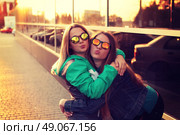 Close up fashion portrait of two young hipster girl friends, wearing mirrored sunglasses, having blonde and ombre hairs. Стоковое фото, агентство Ingram Publishing / Фотобанк Лори