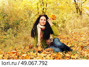 Excited happy fall woman smiling joyful and blissful holding autumn leaves outside in colorful fall forest. Young woman in beautiful autumn park, concept autumn. Стоковое фото, агентство Ingram Publishing / Фотобанк Лори