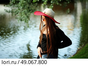 Beautiful young hippie girl outdoors enjoying nature. Trendy boho fashion Caucasian woman wearing black cardigan, hat and denim jeans. Стоковое фото, агентство Ingram Publishing / Фотобанк Лори