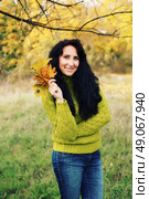 Excited happy fall woman smiling joyful and blissful holding autumn leaves outside in colorful fall forest. Young woman in beautiful autumn park, concept autumn. Стоковое фото, агентство Ingram Publishing / Фотобанк Лори