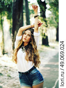 Fashion portrait of beautiful hippie young woman wearing boho chic clothes and summer hat outdoors. Soft warm vintage color tone. Artsy bohemian style. Стоковое фото, агентство Ingram Publishing / Фотобанк Лори