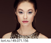 Portrait of beautiful young woman in a shiny golden dress. Brunette girl. Perfect make-up. Freckles. Стоковое фото, агентство Ingram Publishing / Фотобанк Лори