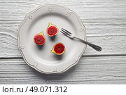 figs raw cutted fig fruits on white plate and wooden table. Стоковое фото, агентство Ingram Publishing / Фотобанк Лори