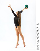 Young girl engaged art gymnastic on grey. Стоковое фото, агентство Ingram Publishing / Фотобанк Лори