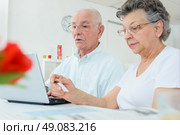 Elderly couple on computer, wife holding credit card. Стоковое фото, агентство Ingram Publishing / Фотобанк Лори