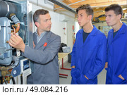Man explaining workings of boiler to two trainees. Стоковое фото, агентство Ingram Publishing / Фотобанк Лори