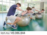 Two men being held in position on aerobic balls. Стоковое фото, агентство Ingram Publishing / Фотобанк Лори