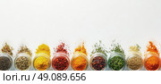 Various colorful spices and herbs in jars with powder and seeds scattered on a white background. Perfect for cooking, food, and spice-related content. Стоковое AI-изображение, AI-художник Катерина Бондарец / Фотобанк Лори