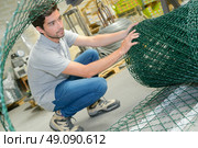 Man unrolling fencing wire. Стоковое фото, агентство Ingram Publishing / Фотобанк Лори