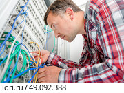 Computer technician checking wiring going to server. Стоковое фото, агентство Ingram Publishing / Фотобанк Лори