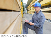 Man with clipboard assessing stack of wood. Стоковое фото, агентство Ingram Publishing / Фотобанк Лори