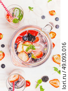 Jug with Infused detox water and berries on white wooden background, top view, close up. Стоковое фото, агентство Ingram Publishing / Фотобанк Лори