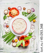 Risotto rice dish  and various vegetables and seasoning ingredients  for tasty vegetarian cooking on light  rustic wooden background, top view composing. Healthy eating and diet food concept. Стоковое фото, агентство Ingram Publishing / Фотобанк Лори