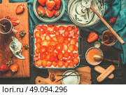 Italian Cuisine, strawberry tiramisu cake preparation with cooking ingredients and kitchen tools on dark vintage background, top view. Italian food concept. Стоковое фото, агентство Ingram Publishing / Фотобанк Лори